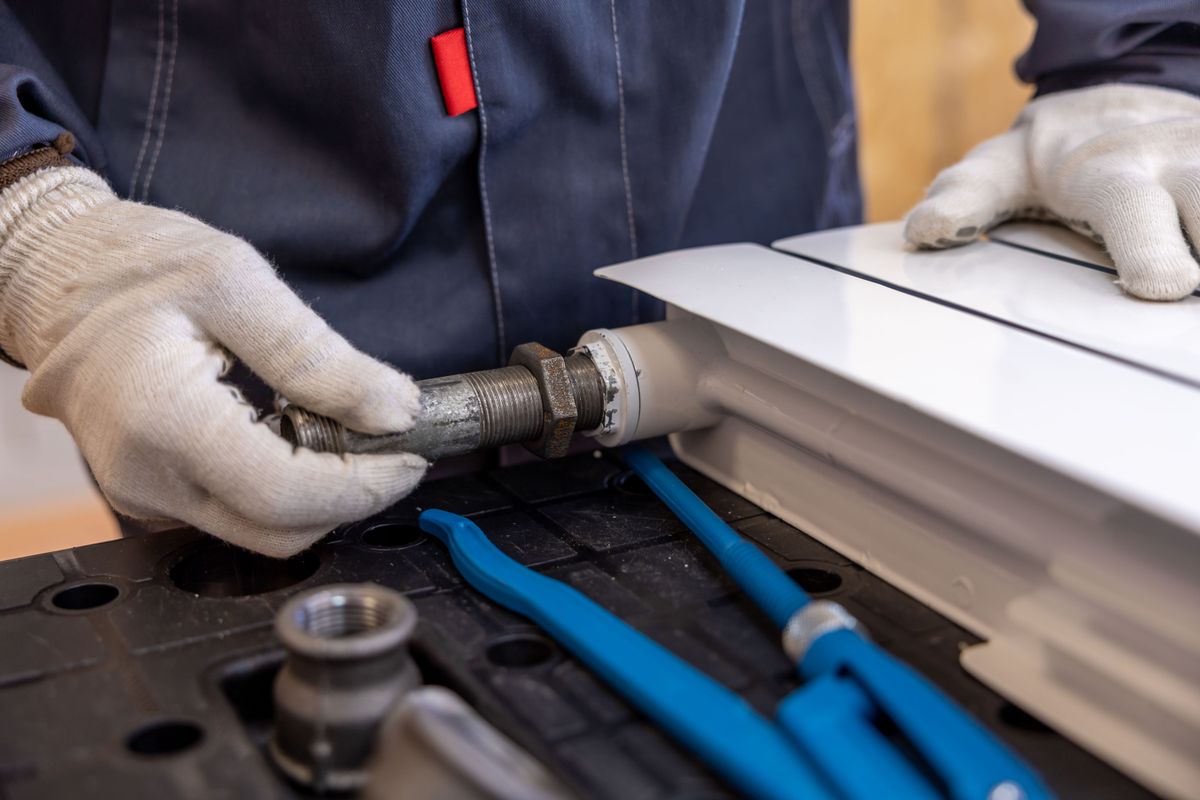 Copper State plumber joining a threaded water line with pipe wrenches